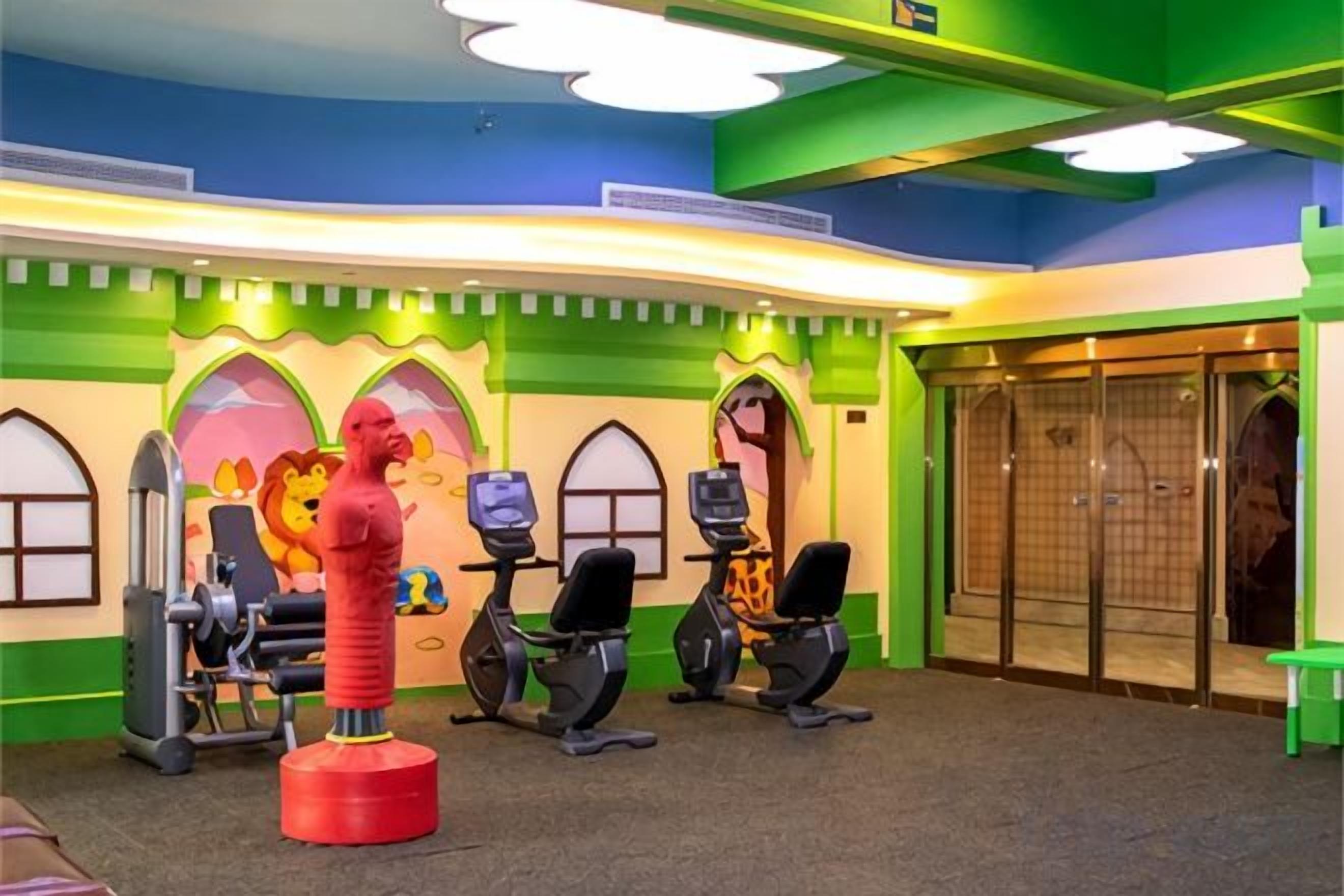 A gym with exercise equipment, a lion statue, and a colorful wall design.