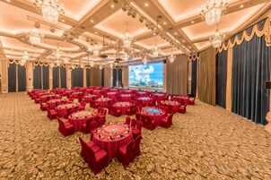 Un amplio salón de banquetes con mesas redondas, un escenario y una gran pantalla.