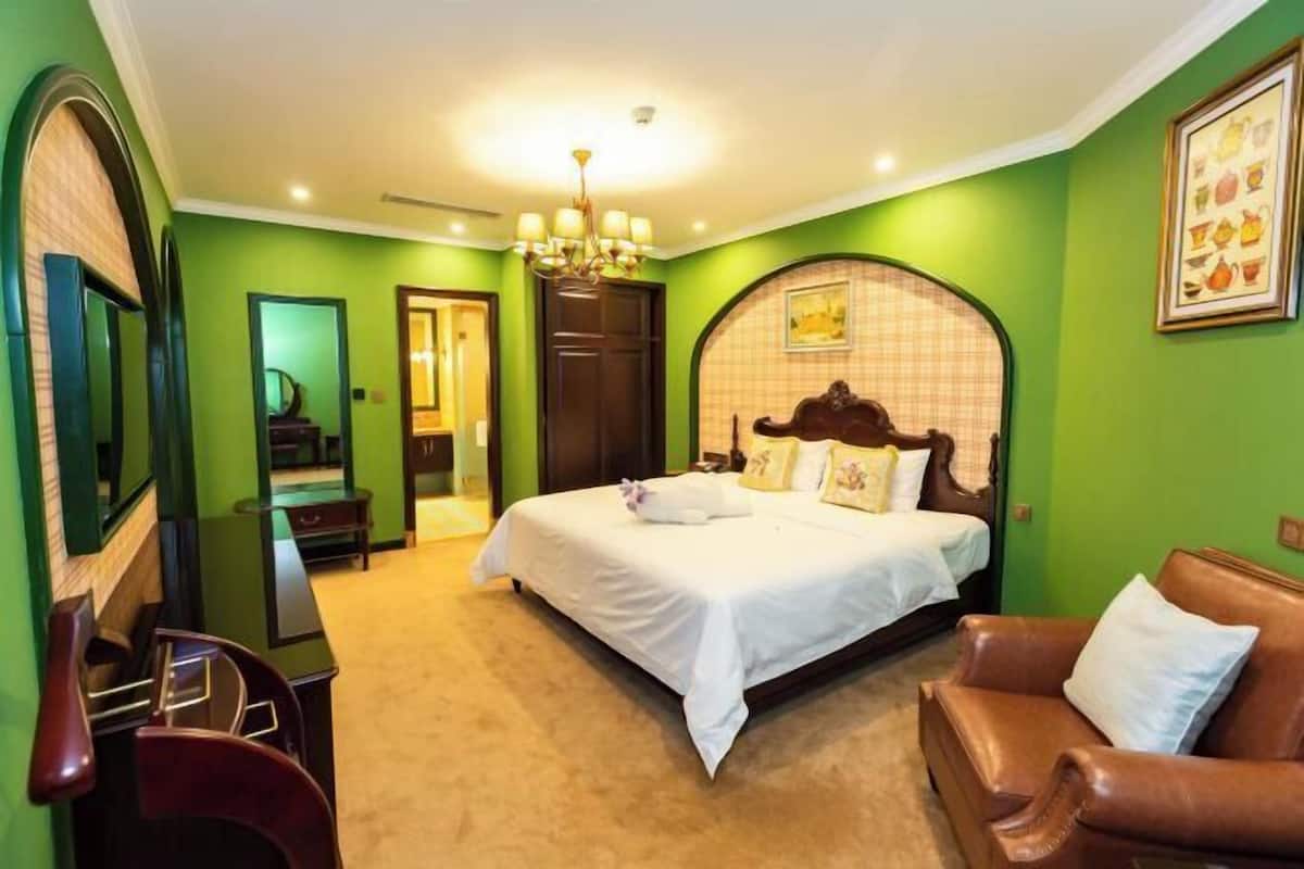 Habitació d'hotel amb un llit gran, un sofà de pell marró, un escriptori i un mirall.
