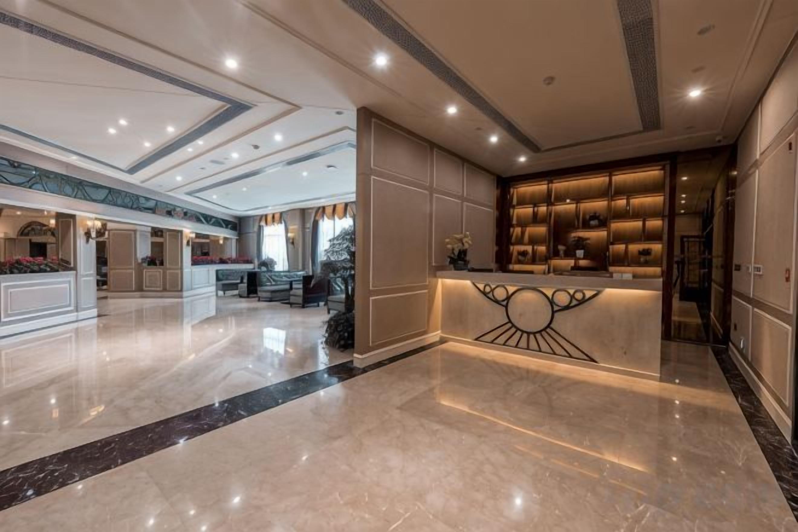 Um saguão de hotel com piso de mármore, balcão de recepção e área de estar.