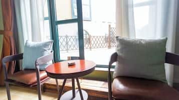 A room with two leather chairs, a small round table, and a window with a view of a balcony.