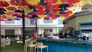 A bar area with a ceiling adorned with colorful umbrellas and a bar counter with stools.