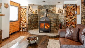 Ein gemütliches Wohnzimmer mit Kaminofen, Ledersofa und Steinwand.