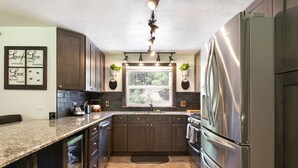 Eine moderne Küche mit dunklen Holzschränken, Edelstahlgeräten, Granitarbeitsplatten und einem Fenster für natürliches Licht.