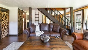 Ein geräumiges Wohnzimmer mit einer Ledersofa, einem Holztisch und einer Treppe mit Metallgeländer.