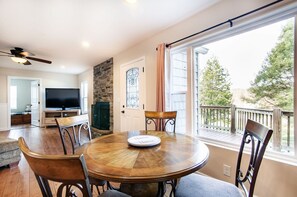 A dining area with a round wooden table, four chairs, a television, and a stone fireplace.