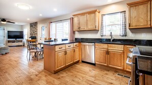 A spacious kitchen with wooden cabinets, a central island, and a built-in dishwasher. - Relax on a Scenic Porch Steps from the Historical Trail (Townsend)