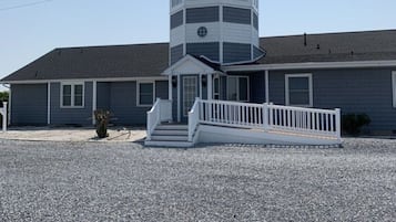 A two-story building with a central tower, a front porch, and a gravel driveway.