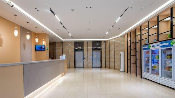 A modern hotel lobby with a reception desk, a television, vending machines, and a clean, tiled floor. - Jiabaihe Hotel (Buyong Subway Station Branch) (Shenzhen)