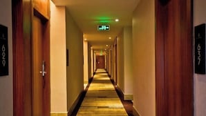 A hotel hallway with wooden doors, numbered room signs, and a carpeted floor. - Jiabaihe Hotel (Buyong Subway Station Branch) (Shenzhen)