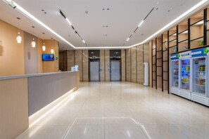 A hotel reception area with a reception desk, a television, and vending machines. - Jiabaihe Hotel (Buyong Subway Station Branch) (Shenzhen)