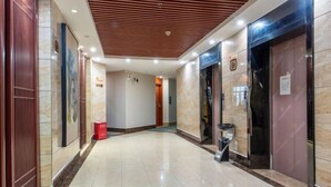A hotel lobby with a polished marble floor, a wooden ceiling, and a modern elevator. - Jiabaihe Hotel (Buyong Subway Station Branch) (Shenzhen)