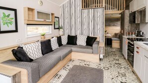 A modern kitchen with white cabinets, a built-in oven, and a hanging light fixture. - Hillside Lodge (Llandrindod Wells)
