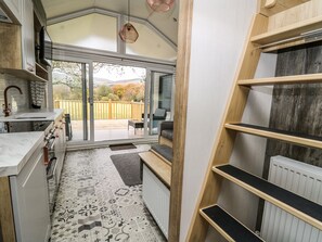 A compact kitchen with a large sliding glass door leading to a deck, a built-in bench, and a radiator.