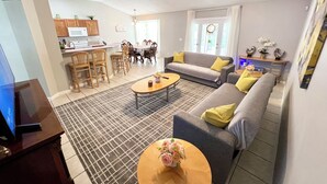 Un grand espace de vie comprenant un canapé, une table basse et une table à manger. Il y a également un coin cuisine avec des meubles en bois et un ensemble de salle à manger.