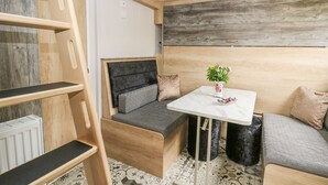 Ein kleines Zimmer mit einem hölzernen Bett, einem kleinen Tisch mit einer Vase und einer Bank.
