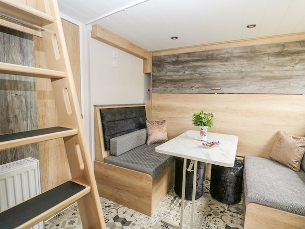 A compact room with a wooden bed, a small table with a vase, and a bench. - Hares Rest (Llandrindod Wells)