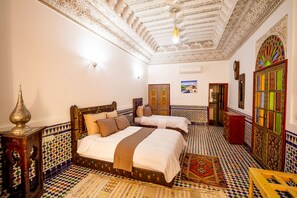 A room with a large bed, a wooden nightstand, a patterned rug, and a decorative ceiling. - Riad Sayeda Al Hora (Fes)