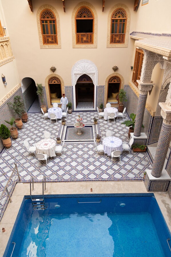 A poolside area with tiled flooring, outdoor seating, and a pool. - Riad Sayeda Al Hora (Fes)