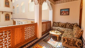 A traditional Moroccan interior with ornate wooden lattice work, a patterned sofa, and a checkered floor. - Riad Sayeda Al Hora (Fes)