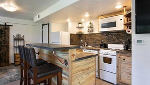Una cocina compacta con isla central, electrodomésticos blancos y diseño rústico de madera.