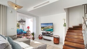 Een moderne woonkamer met een bank, televisie en een houten trap.