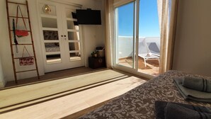 Een kamer met een bed, een televisie, een schuifdeur naar een balkon en een houten vloer.