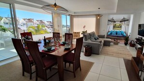 Een moderne woonkamer met een eethoek, een bank, een televisie en een trap.