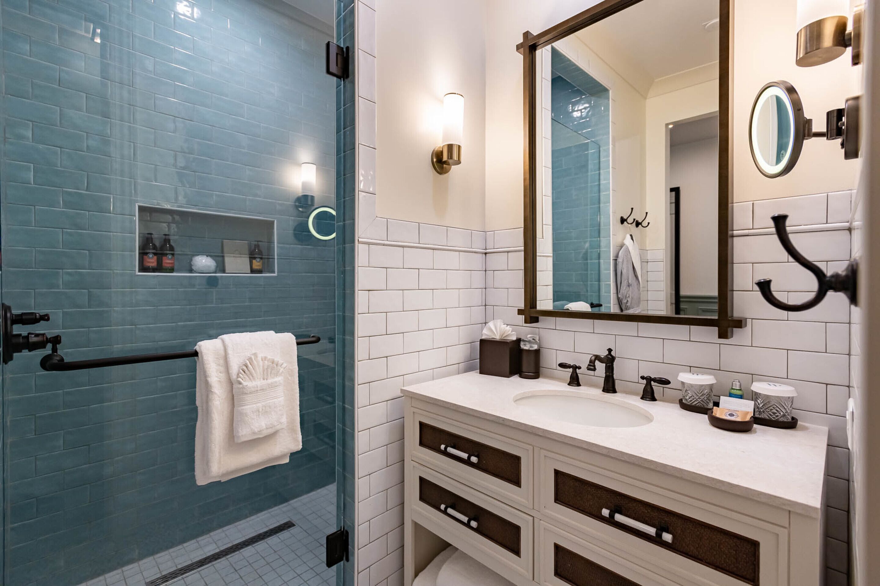 A bathroom with a glass shower enclosure, a white sink with a mirror, and a towel rack.