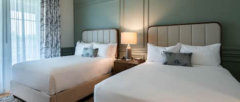 A hotel room with two beds, a nightstand with a lamp, and a window with sheer curtains.