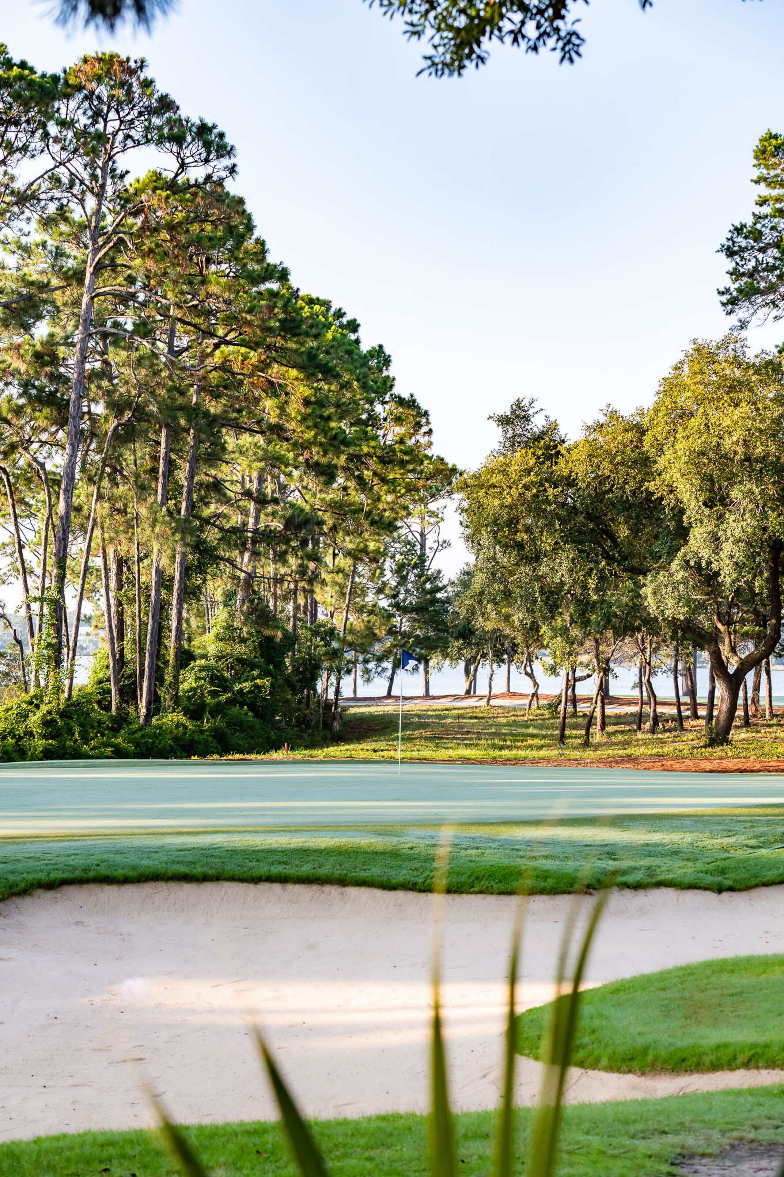 Un campo de golf con búnkeres de arena, árboles y cielo despejado.