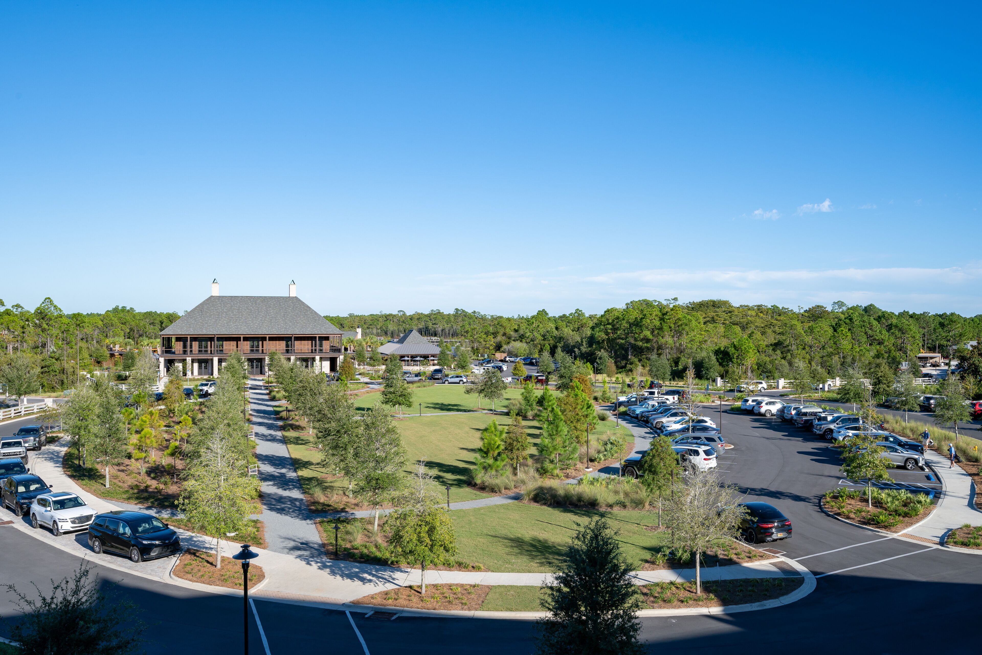 A large building with a parking lot and surrounding greenery.