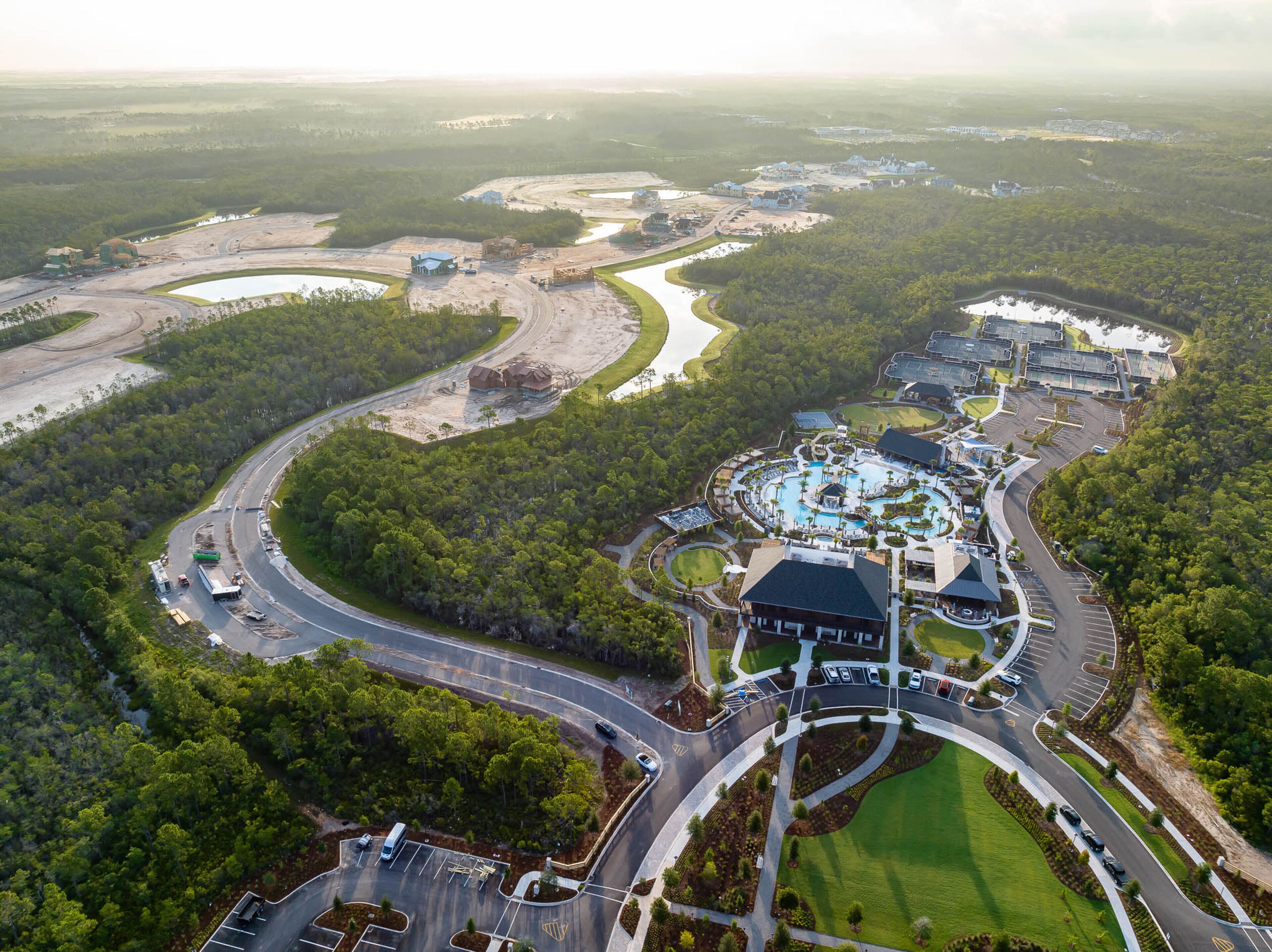 An aerial view of a resort with a large swimming pool, multiple buildings, and winding roads.