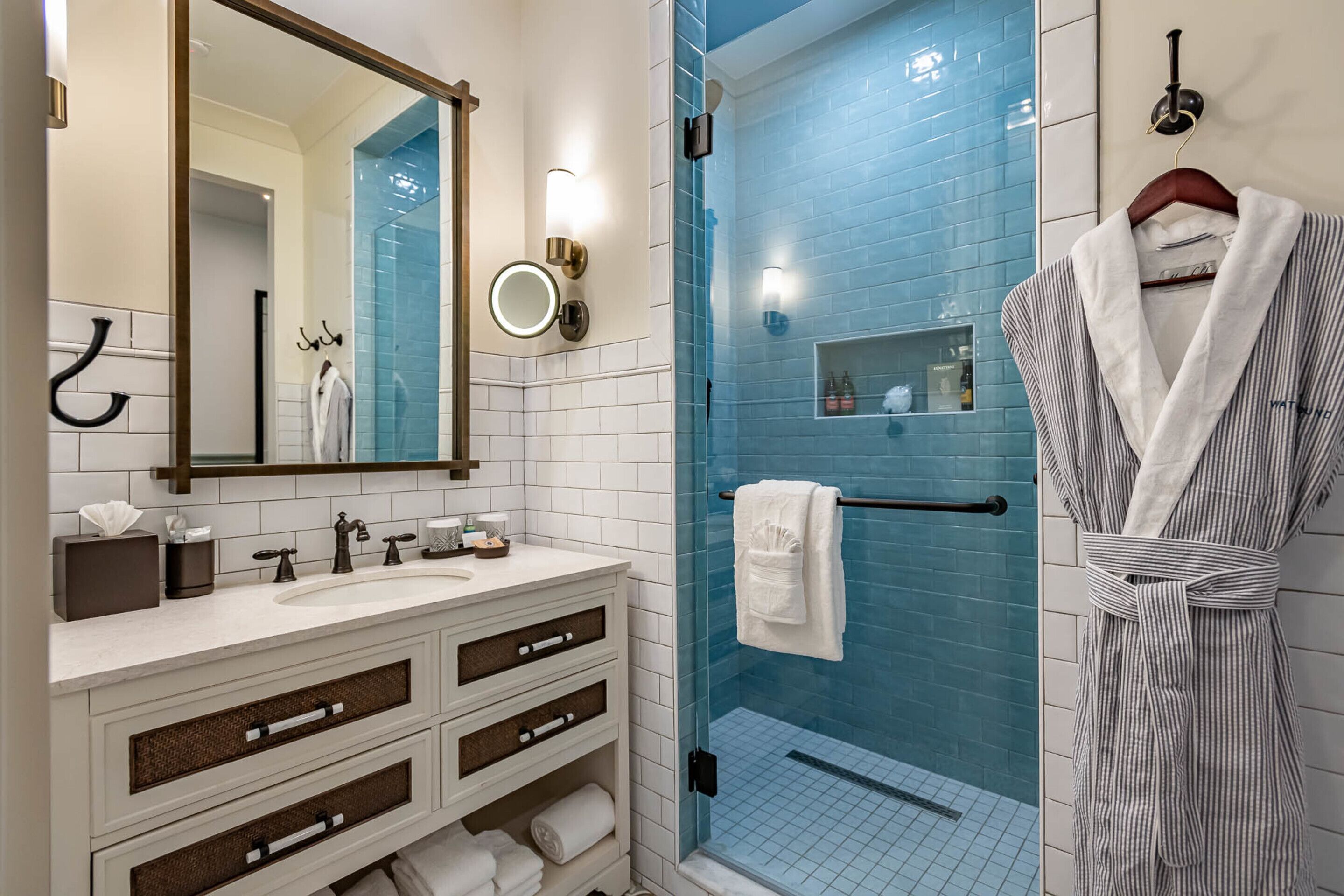 A modern bathroom with a large mirror, white vanity, and a glass shower enclosure.