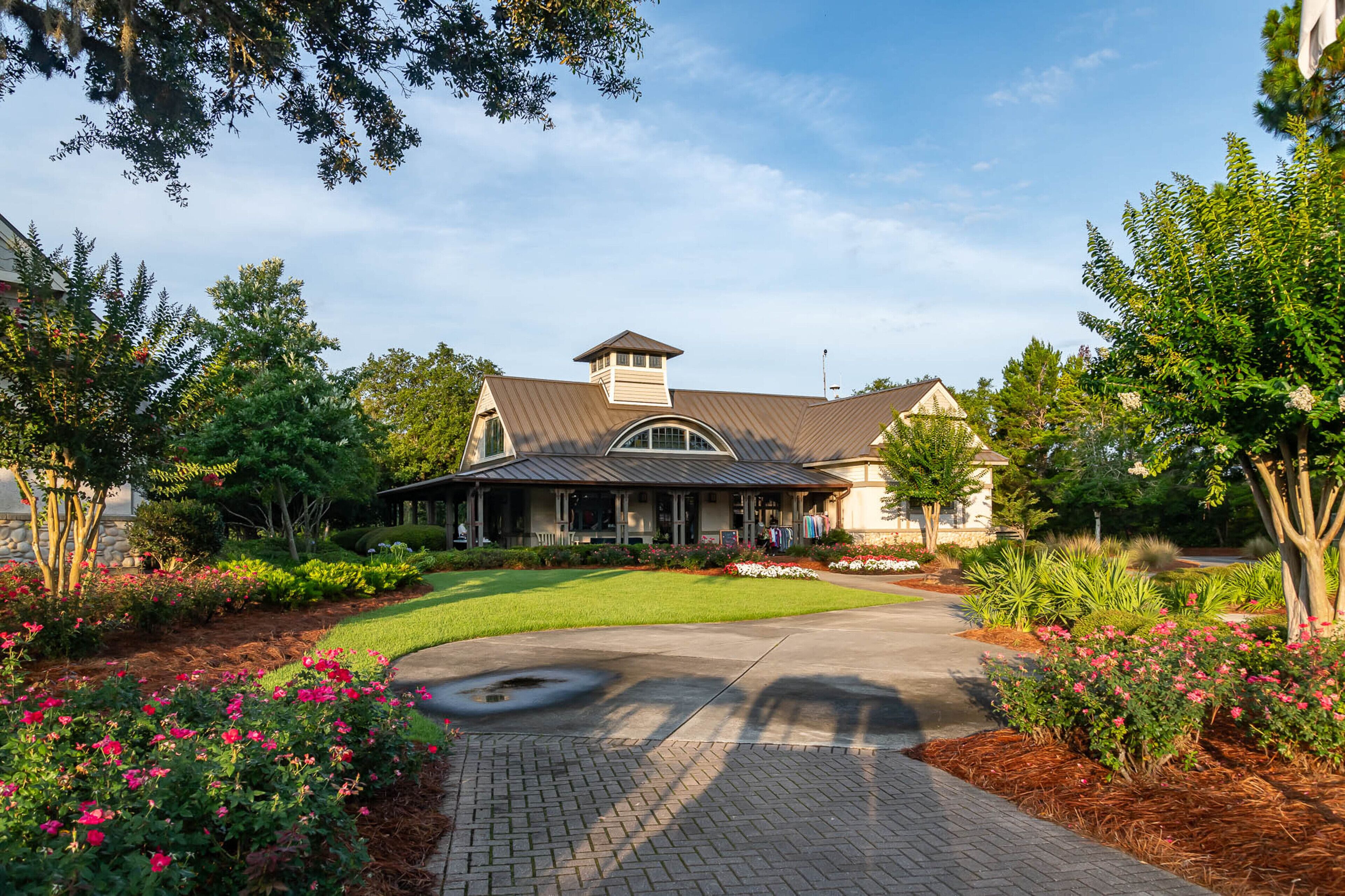 A two-story house with a covered porch, surrounded by well-maintained gardens and a paved driveway.