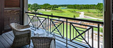 Un balcón con mobiliario de mimbre y vistas a un campo de golf.