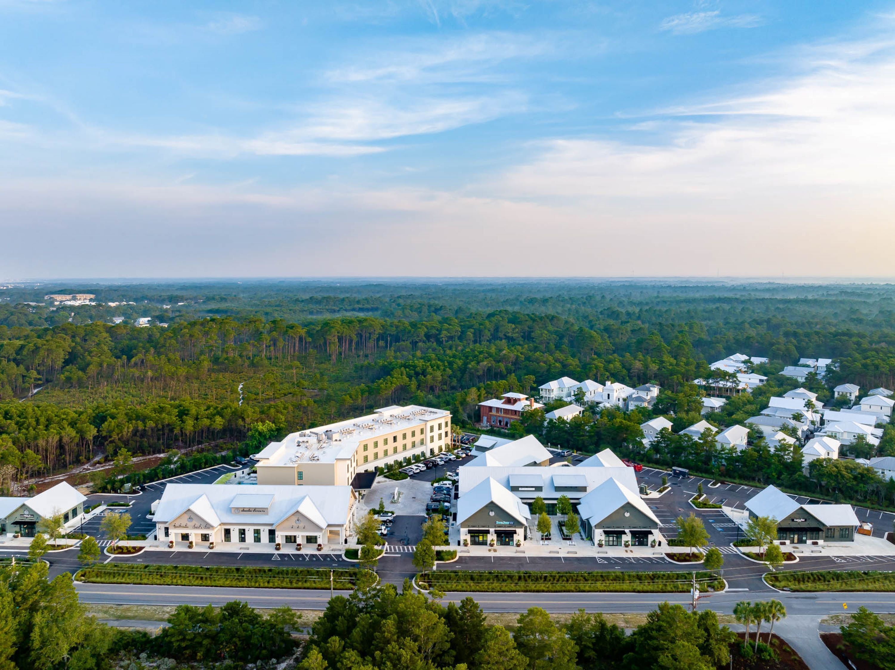 Ein großer, moderner Hotelkomplex mit mehreren Gebäuden, einem Parkplatz und einer umliegenden Waldlandschaft.