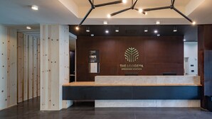 A reception desk with a logo and text indicating 'The Lodge 30A Greenway Station'. - The Lodge 30A (Santa Rosa Beach)