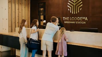 Bancada de recepção na The Lodge 30A Greenway Station, com design moderno e um logotipo na parede.