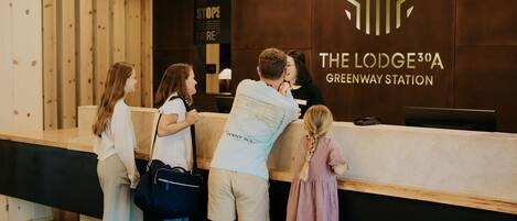 A reception desk at The Lodge 30A Greenway Station with a modern design and a logo on the wall.