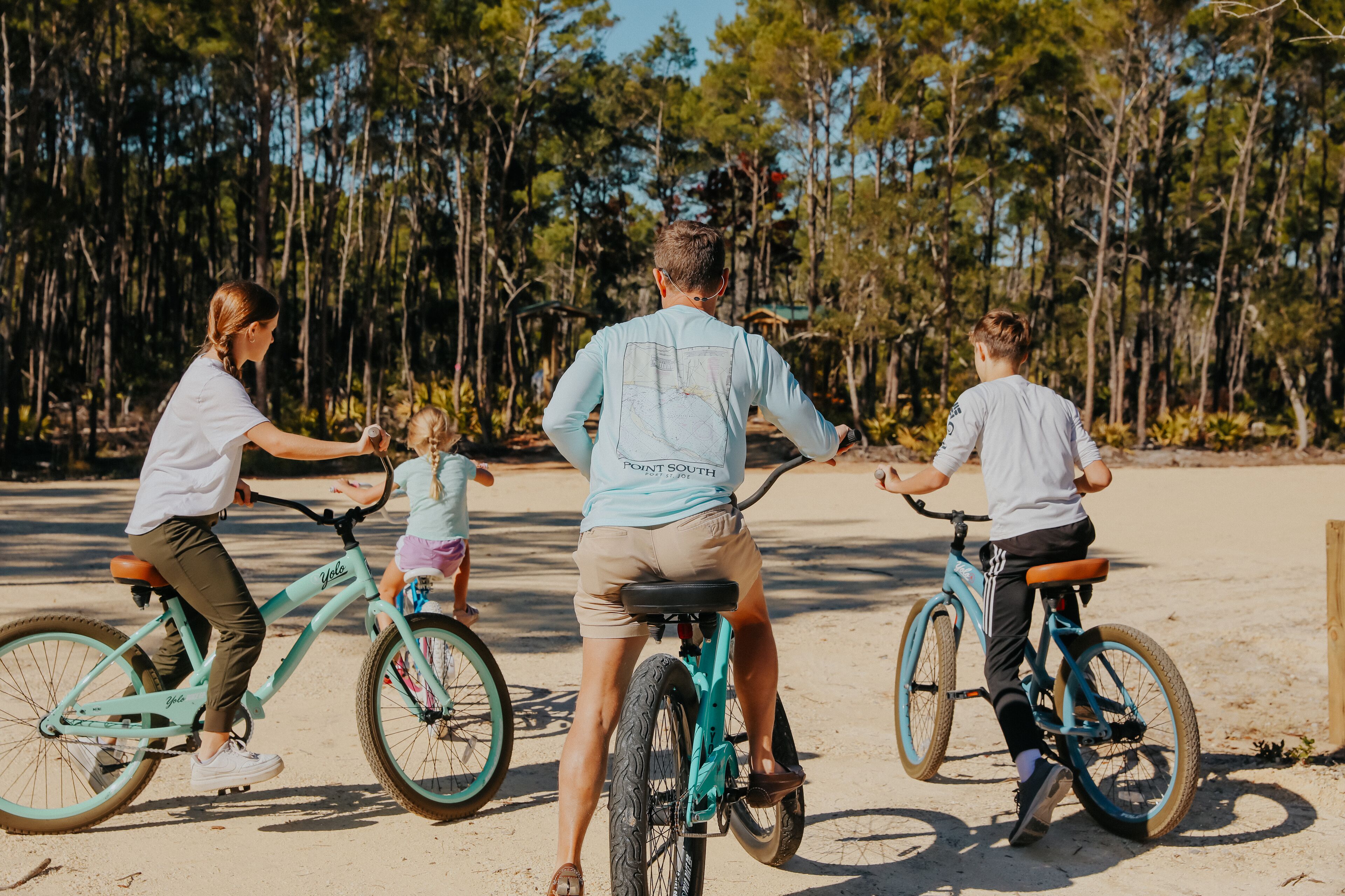 A sandy beach with people riding bicycles.
