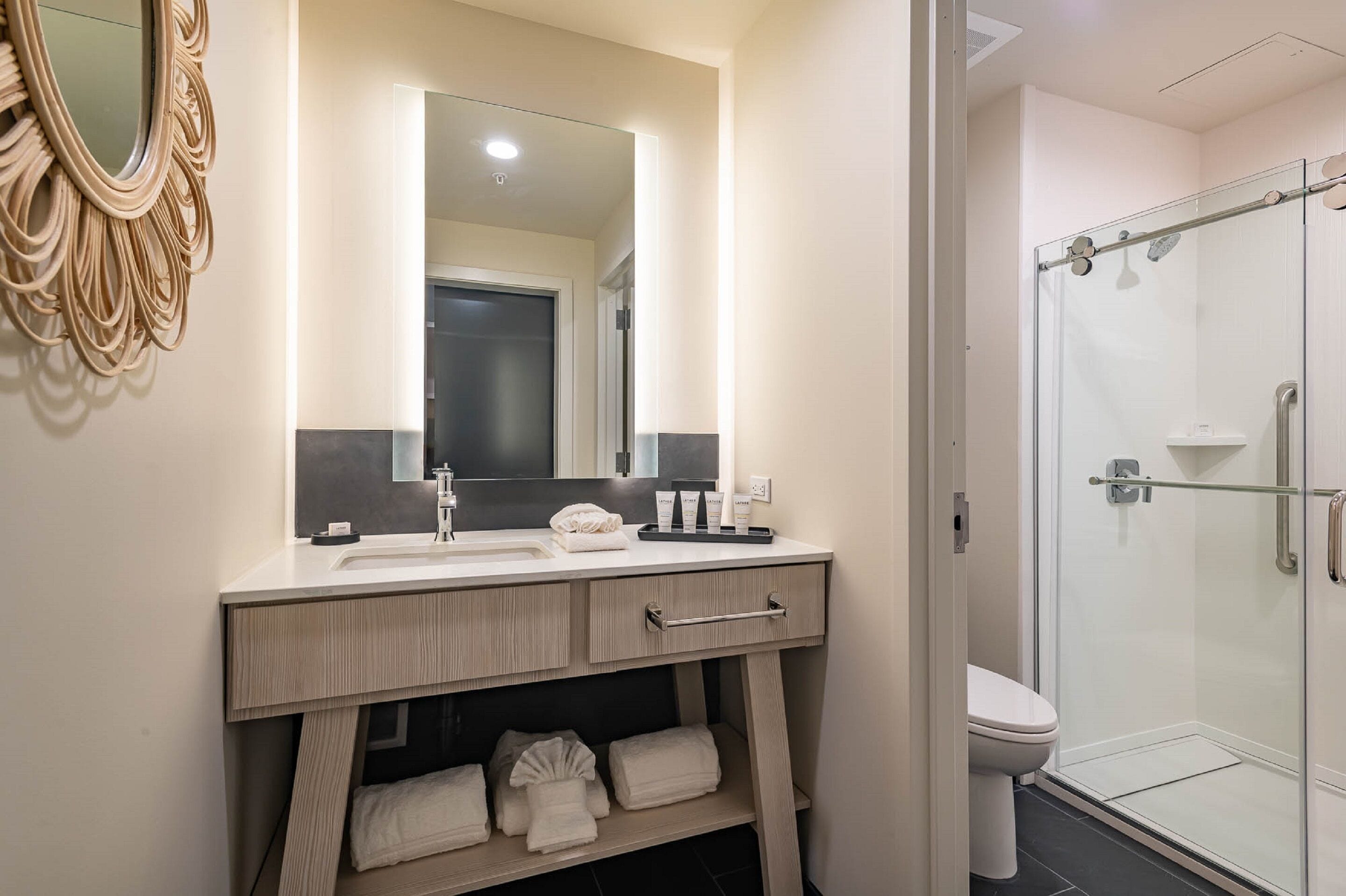 Une salle de bain moderne avec un grand miroir, un lavabo, des toilettes et une douche à parois de verre.