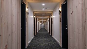 A long, narrow hallway with wooden paneling on the walls and a patterned carpet.