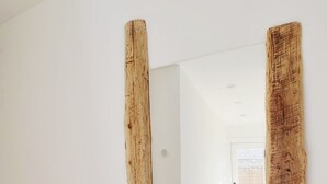 A hallway with wooden beams, a wooden floor, and a door leading to another room.