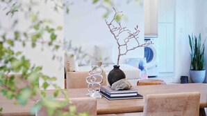 A dining area with a wooden table, a vase with a branch, a book, and a rock.