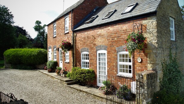 A traditional brick house with a sloped roof, multiple windows, and a gravel driveway. - Lovely Quiet Cottage in Kemerton! (Tewkesbury)