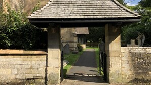 A stone archway leading to a cemetery with tombstones and a statue of an angel. - Lovely Quiet Cottage in Kemerton! (Tewkesbury)