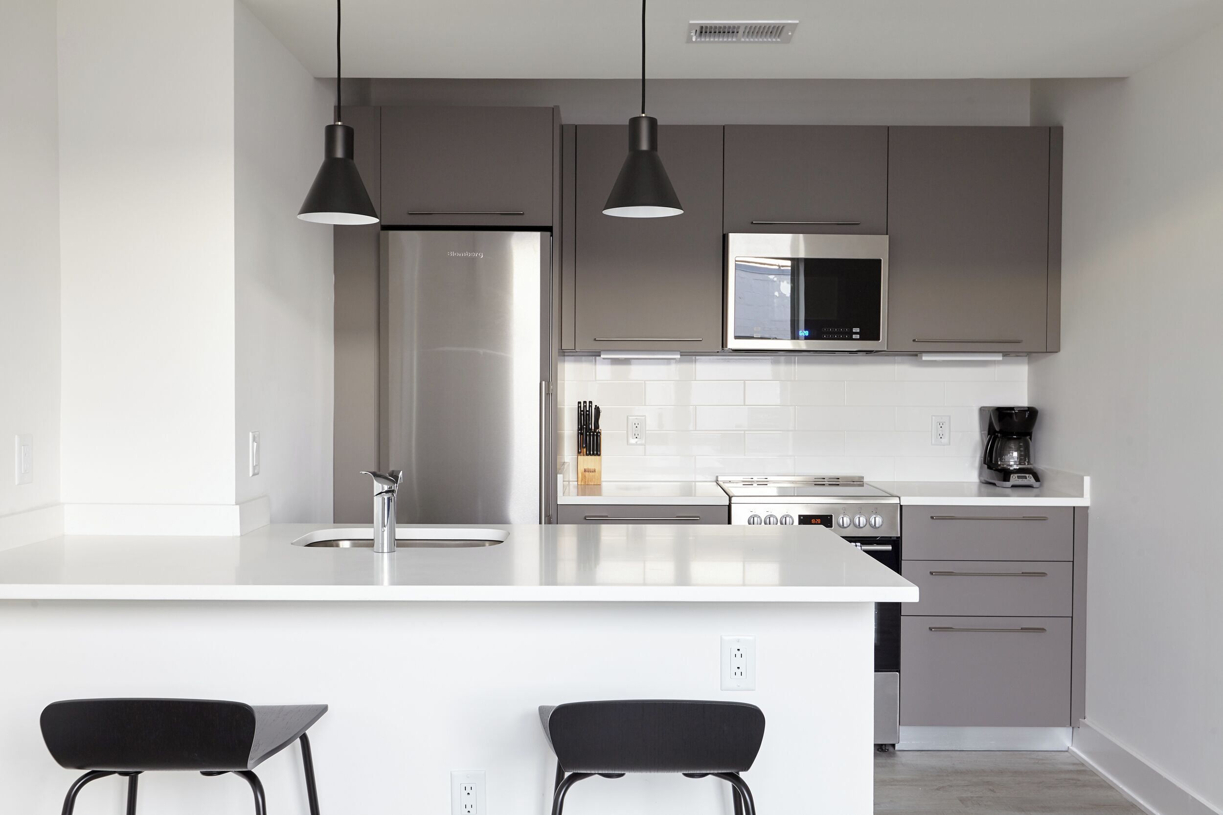 A modern kitchen with a central island, stainless steel appliances, and pendant lighting.