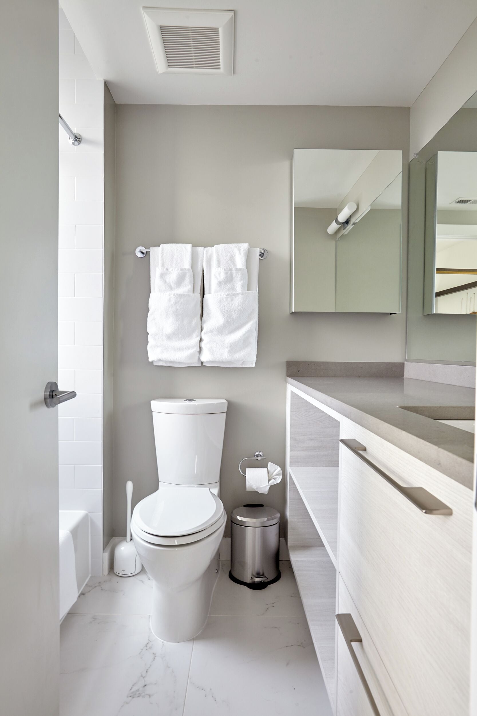 A modern bathroom with a toilet, bidet, and a trash bin.
