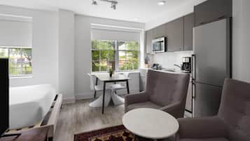 A modern kitchen with grey cabinets, a stainless steel refrigerator, and a dining area with a table and chairs.